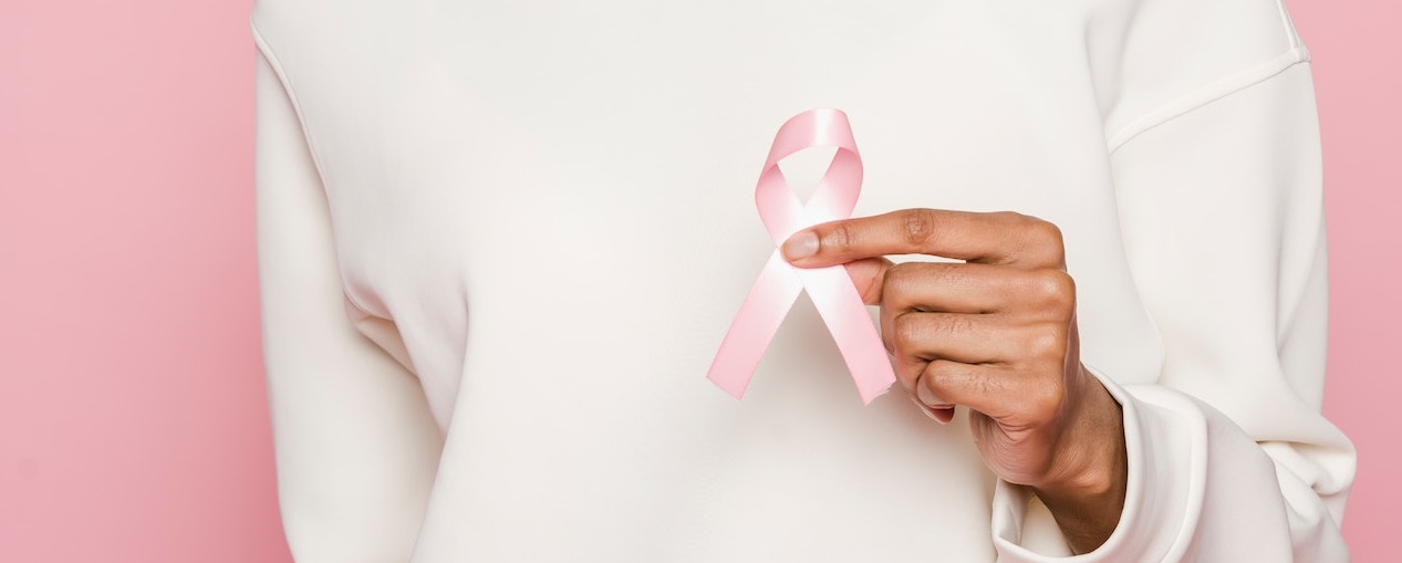 Woman in white holding pink ribbon | Breast Cancer Car Donations