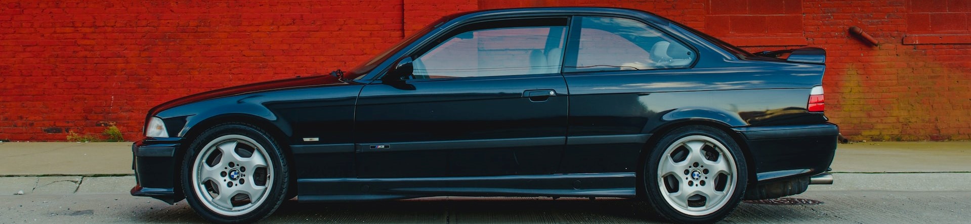 blue sedan parked beside red wall photo | Breast Cancer Car Donations