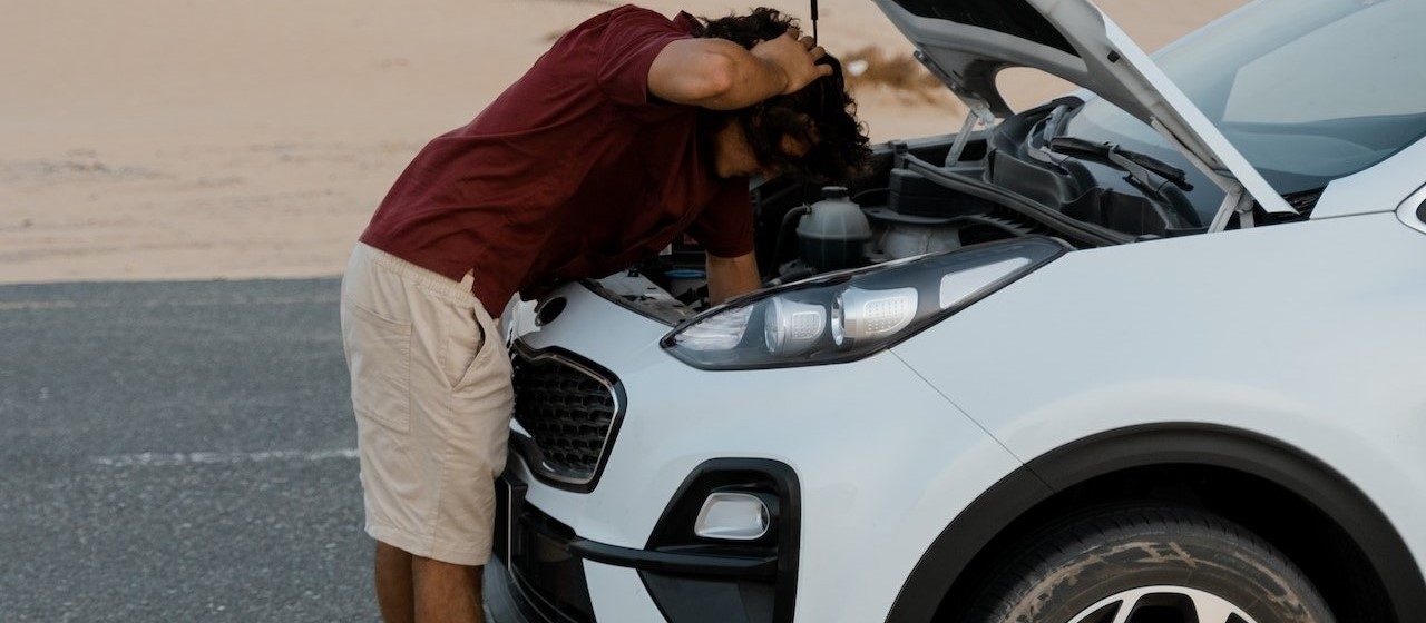 Man fixing his car on the road | Breast Cancer Car Donations