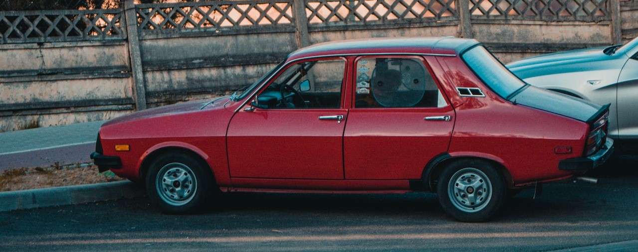 Red Classic Sedan Parked Near Gray Metal Fence | Breast Cancer Car Donations