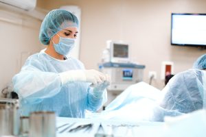 Woman in Blue Dress Shirt Wearing Blue Mask and White Latex Gloves | Breast Cancer Car Donations