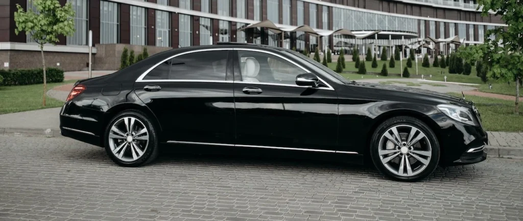 Elegant black sedan parked in front of a modern architectural building, showcasing luxury and style
