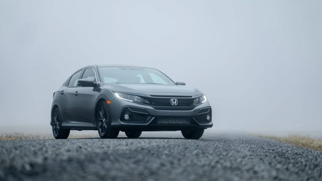 A sleek silver car parked on a foggy road, showcasing its elegance