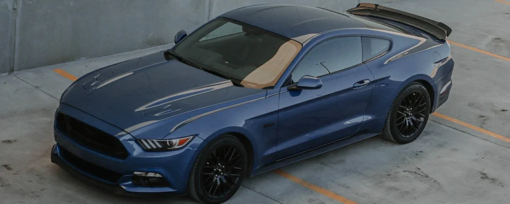A stylish blue Ford Mustang parked in an empty concrete urban parking lot