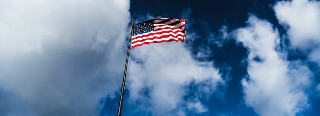 Flag of America on pole under cloudy sky