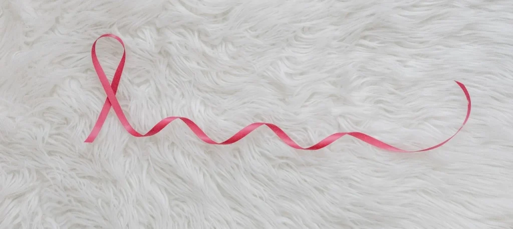Pink ribbon symbolizing breast cancer awareness on a white fur background