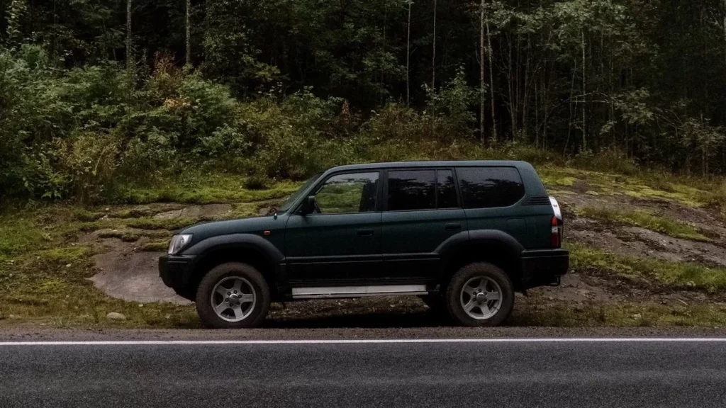 A lone SUV parked on a forest-lined roadside, perfect for travel themes