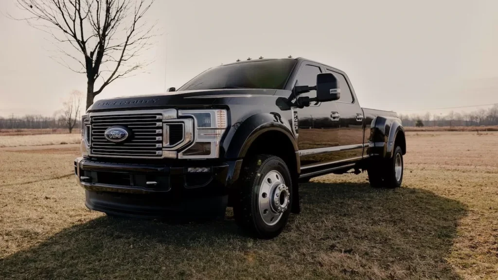 Shiny Ford F450 pickup truck parked in a wide grass field during the day