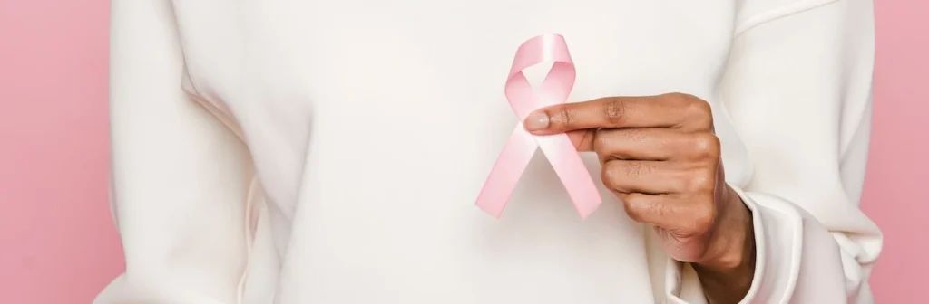 Smiling woman holding a pink ribbon symbolizing breast cancer awareness and support