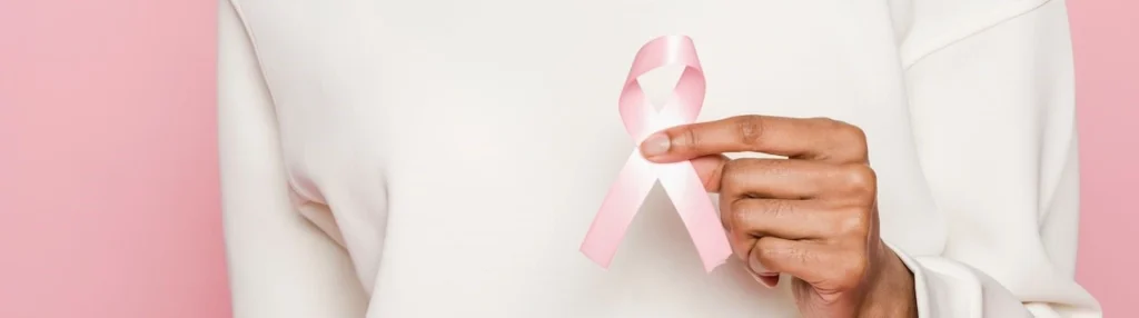 African American woman holding a pink ribbon for breast cancer awareness