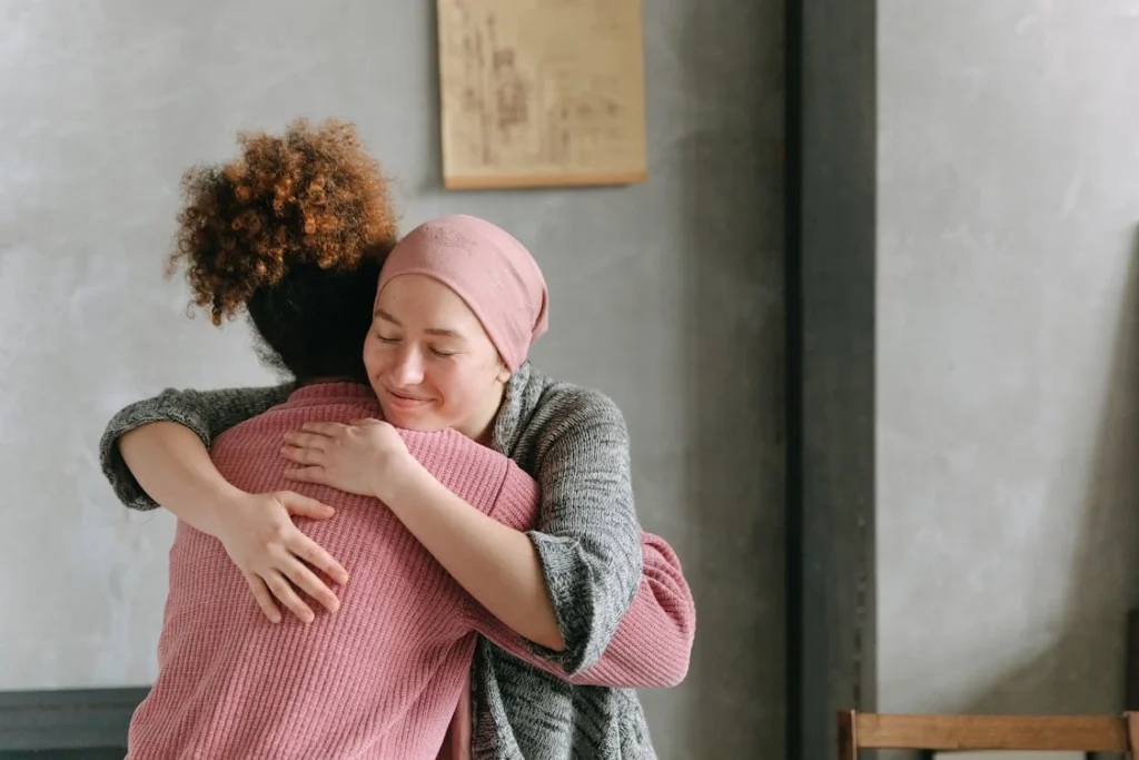 Two women embracing each other with warmth and love, symbolizing support and care indoors