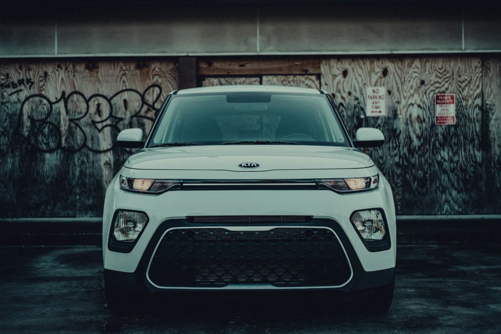 Front view of a white car parked against a graffiti-covered wall, urban setting