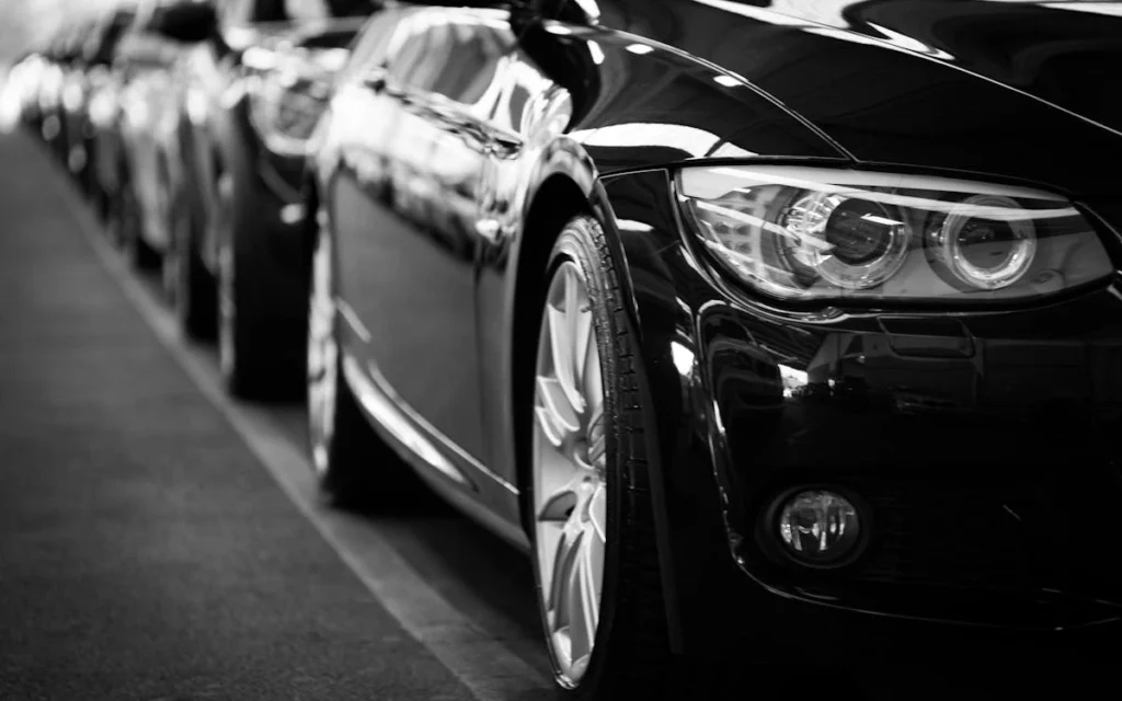 Close-up black and white image of a luxury car line-up focusing on vehicle headlights