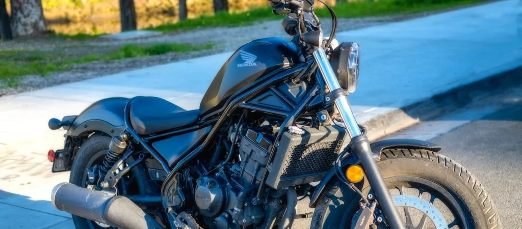 A stylish black motorcycle parked on a sunny street, showcasing details of its engine and tire