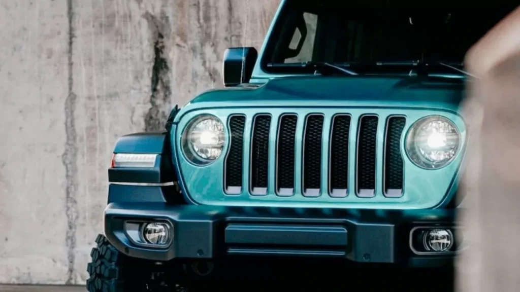 Blue Jeep Wrangler parked in an urban setting with industrial background