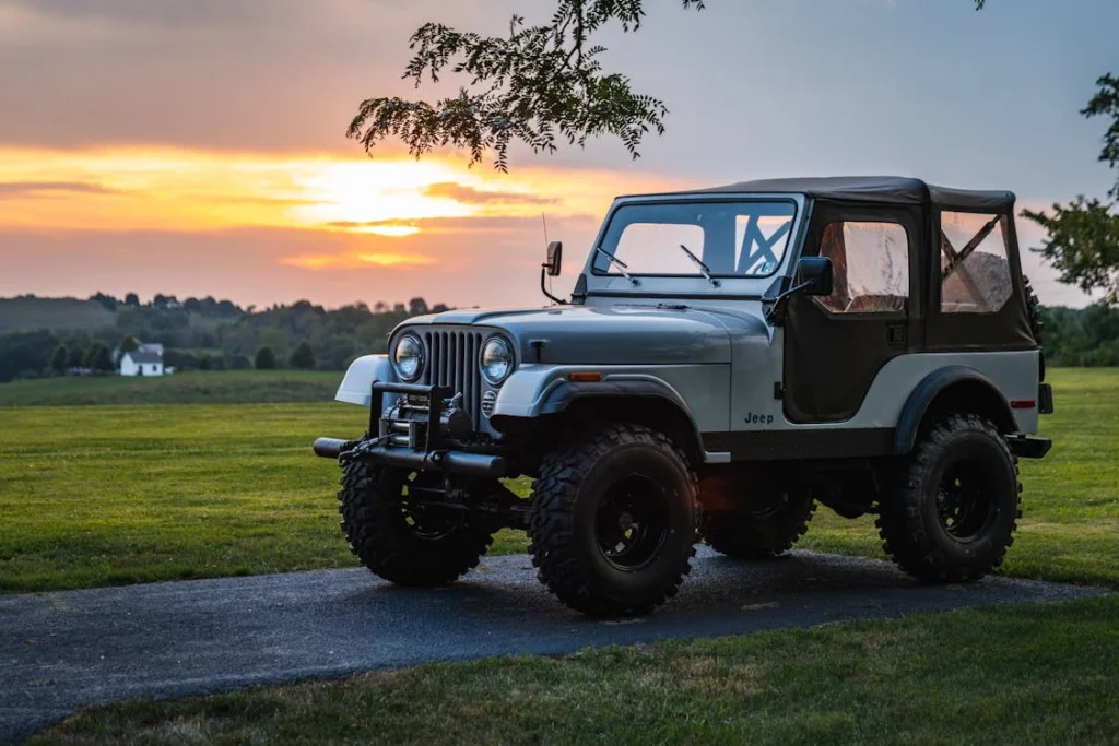 A classic Jeep parked on a rural road at sunset, showcasing a peaceful countryside scene