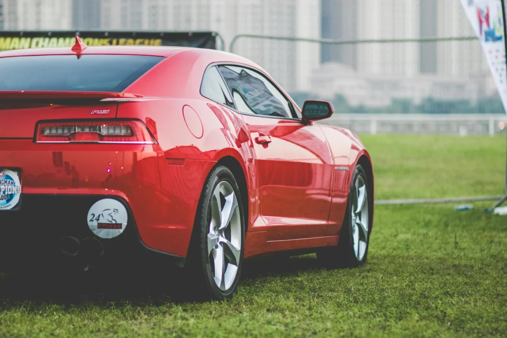 Dynamic red sports car captured outdoors with city skyline backdrop, showcasing luxury and performance