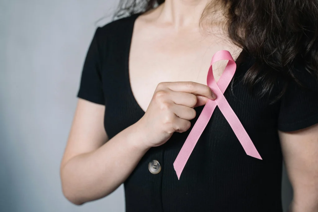Close-up of a woman holding a pink ribbon symbolizing breast cancer awareness and support