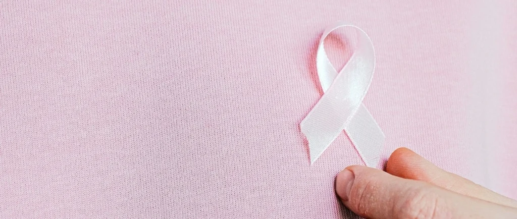 Close-up of a person wearing a pink hoodie with a breast cancer awareness ribbon