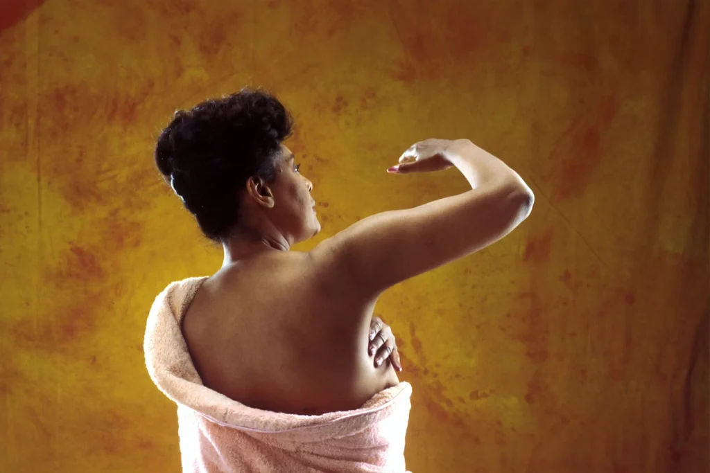 An African American woman performing a breast self-examination (BSE)